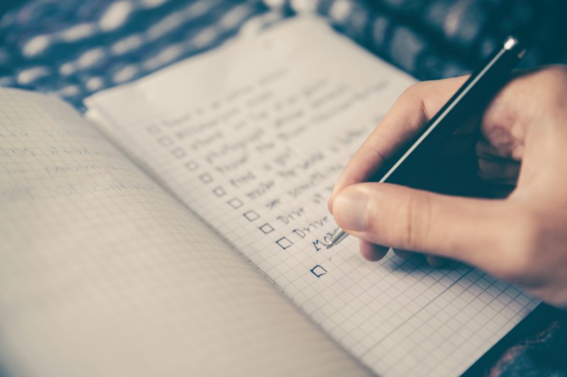 Main écrivant une liste dans un carnet