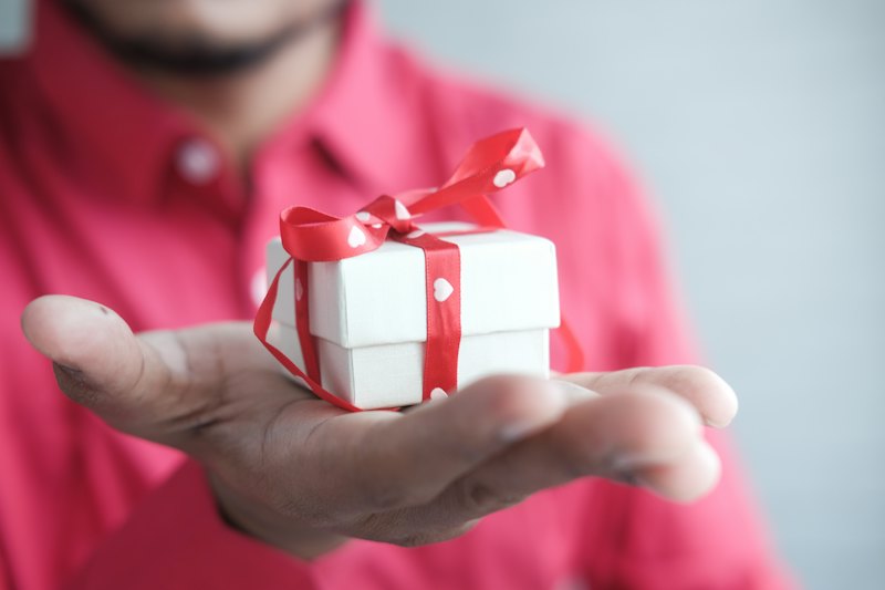 Homme tenant un cadeau blanc à ruban rouge